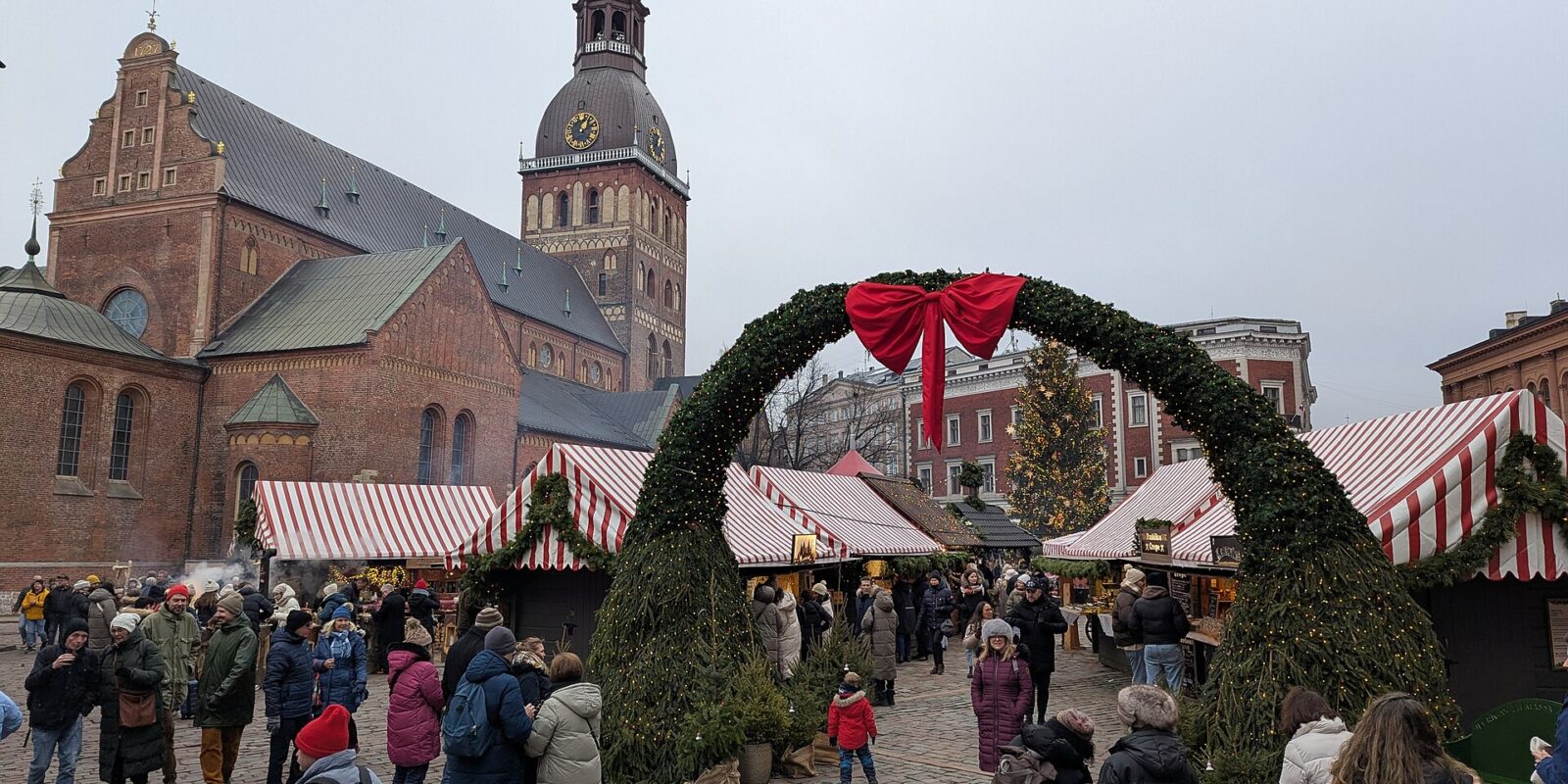 A garland arch and striped market stalls on Dome Square in Riga, with the cathedral tower behind