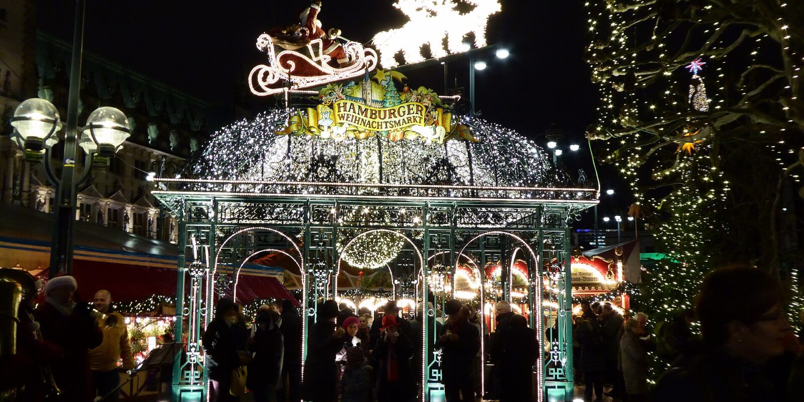 The illuminated entrance arch of the Christmas market on Hamburg Rathausmarkt, topped by Santa's sleigh and reindeer